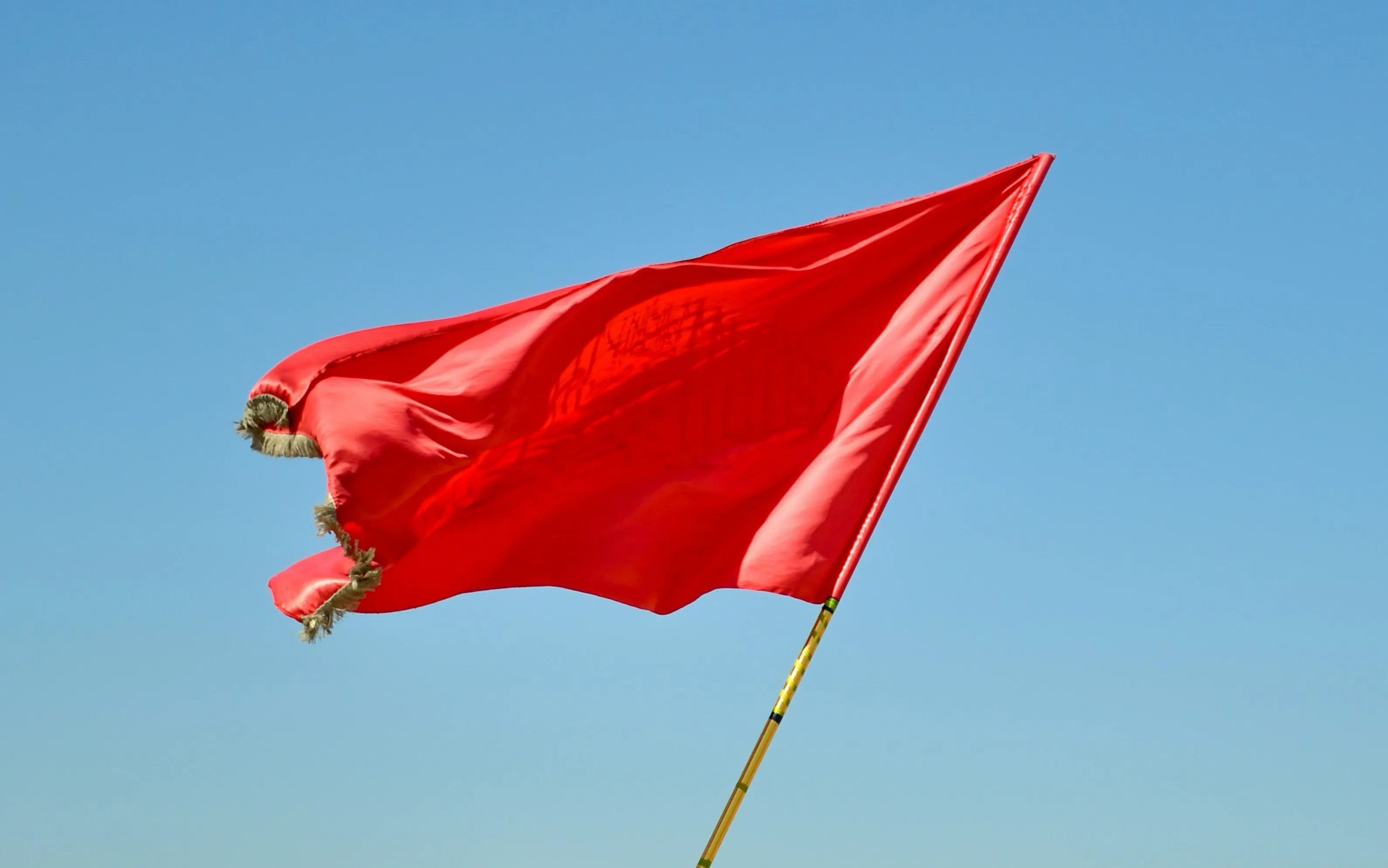 Red flag on a pole under a blue sky